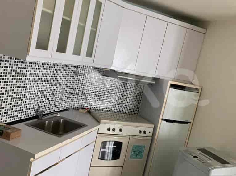 A compact kitchen with white cabinets, a mosaic backsplash, and a refrigerator.