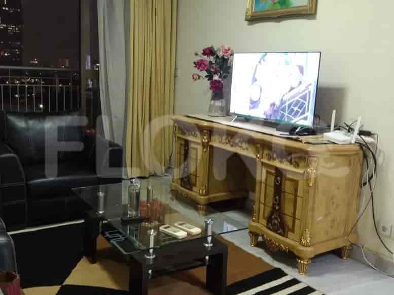 Living room with sofa, TV, and a view of the city at night.
