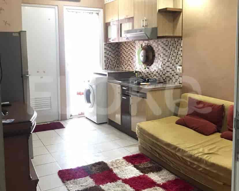 A small kitchen area with a washing machine, adjacent to a living space with a sofa.