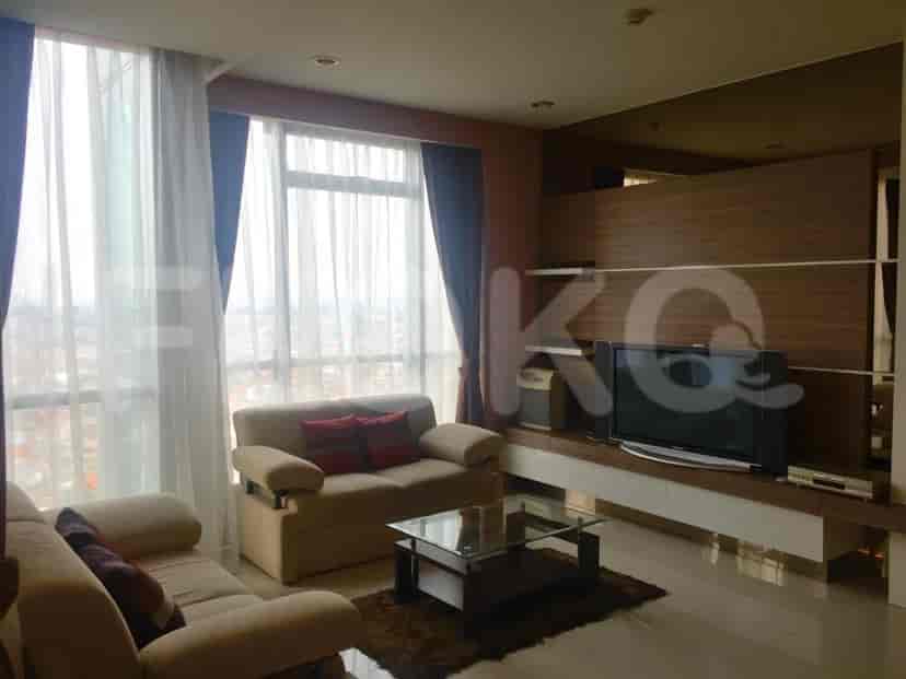 Spacious living room with a beige sofa, TV, and large windows.
