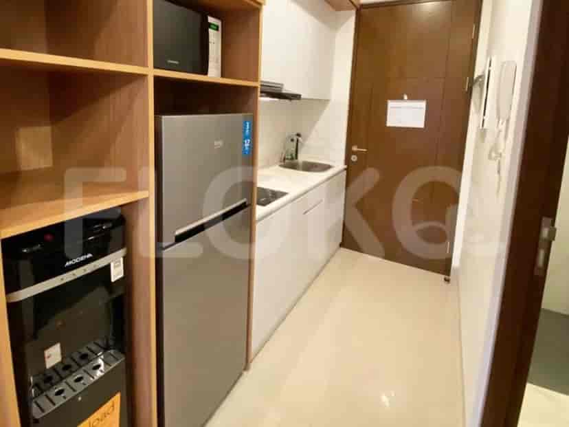 Compact kitchen with refrigerator, sink, and storage cabinets.