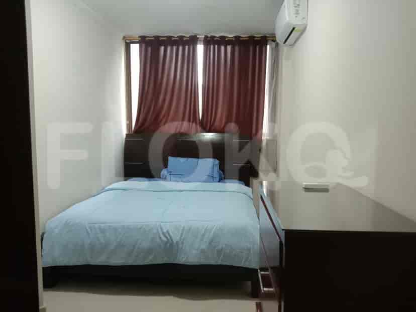A bedroom with a bed, curtains, and an air conditioner.