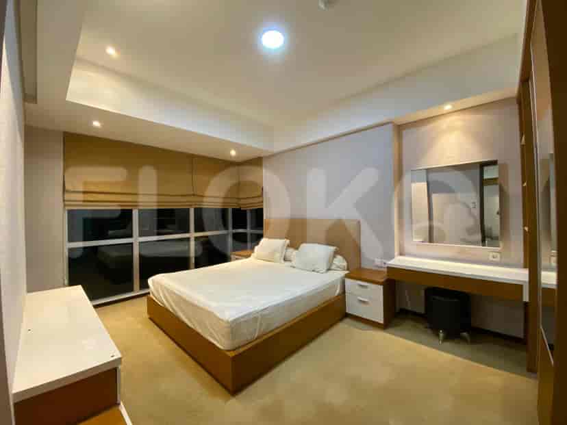 A well-lit bedroom with a large bed, dressing table, and window.