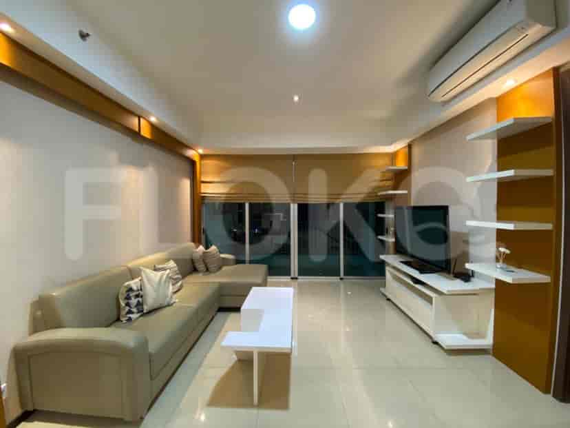 A spacious living room with an L-shaped grey sofa, wall-mounted TV, and large window.
