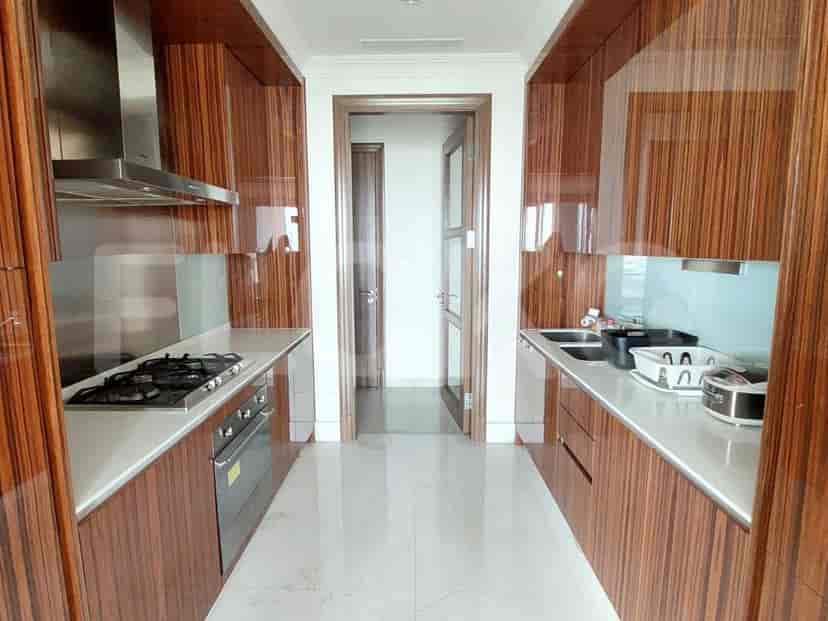 Dapur modern dengan lemari kayu, peralatan stainless steel, dan meja berwarna terang.