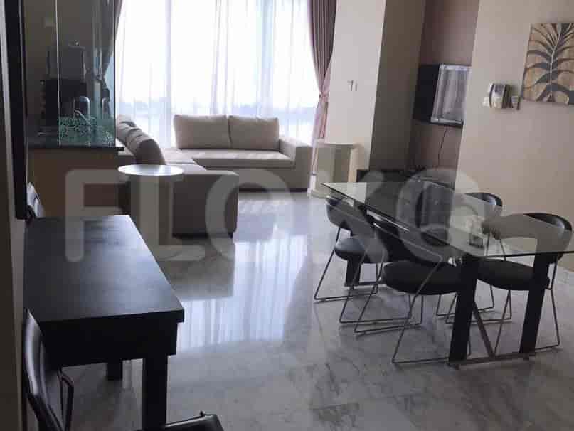 A spacious living room with a large grey sofa, dining area, and a view through a large window.