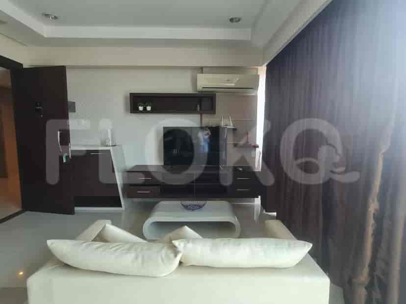 Living room with a TV entertainment unit, white sofa, and a view through the windows.