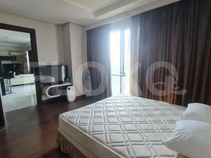 Spacious bedroom with a large bed, dark wooden flooring, and a view through the window.