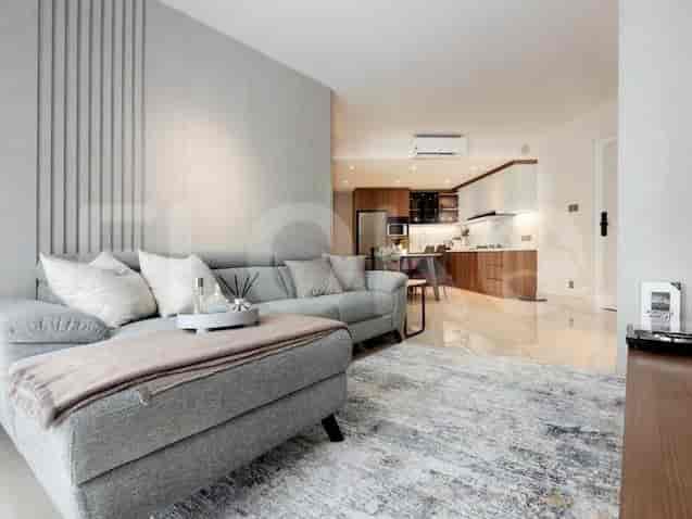 A stylish living room featuring a grey sofa, modern decor, and access to the kitchen.