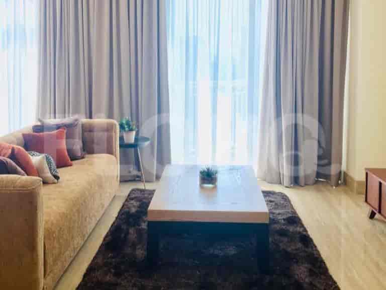 Living room with a brown sofa, coffee table, and sheer curtains.