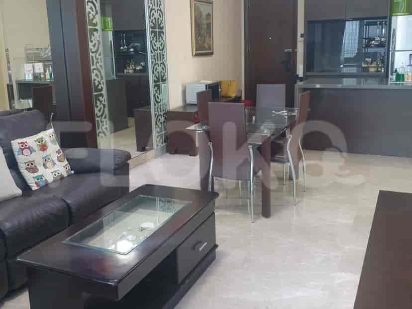 A living room with a glass coffee table, brown sofa, and glass dining table.