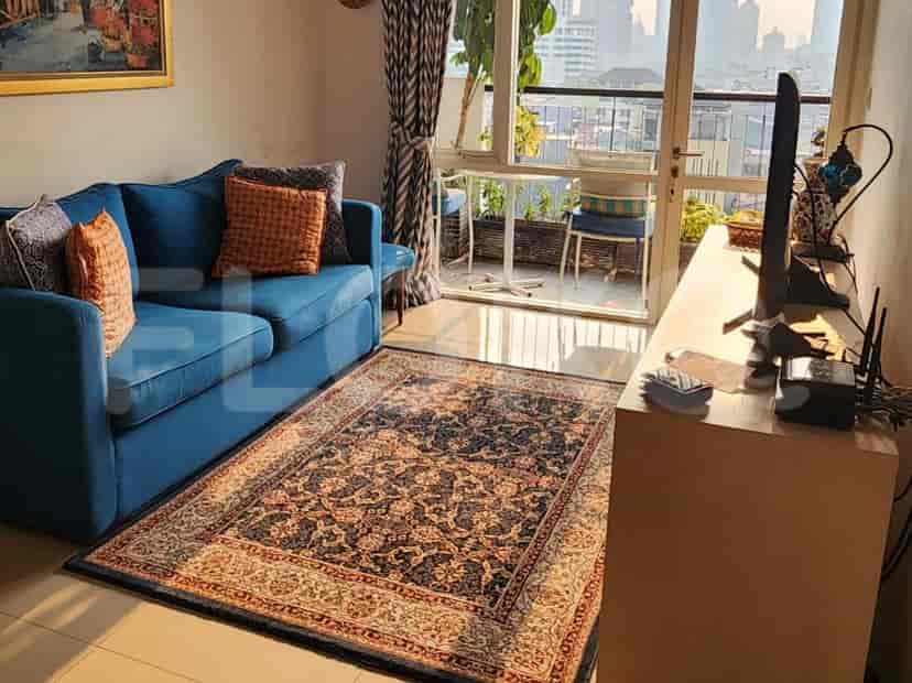 A living room with a blue sofa, rug, and a view of the city.