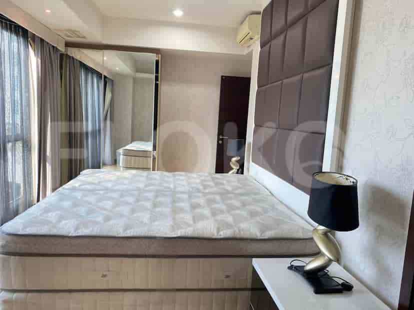 Another bedroom featuring a bed, a mirrored wall, and a side table.