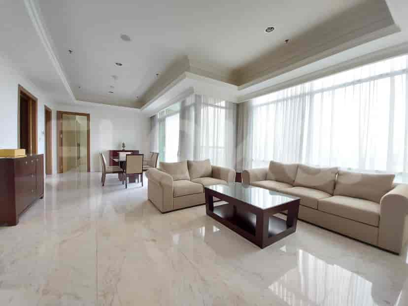 A spacious living area with a large sofa, coffee table, dining table, and ample natural light.