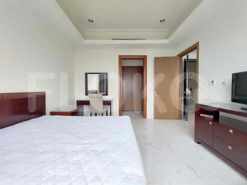 A well-lit master bedroom with a bed, desk, and a built-in closet.