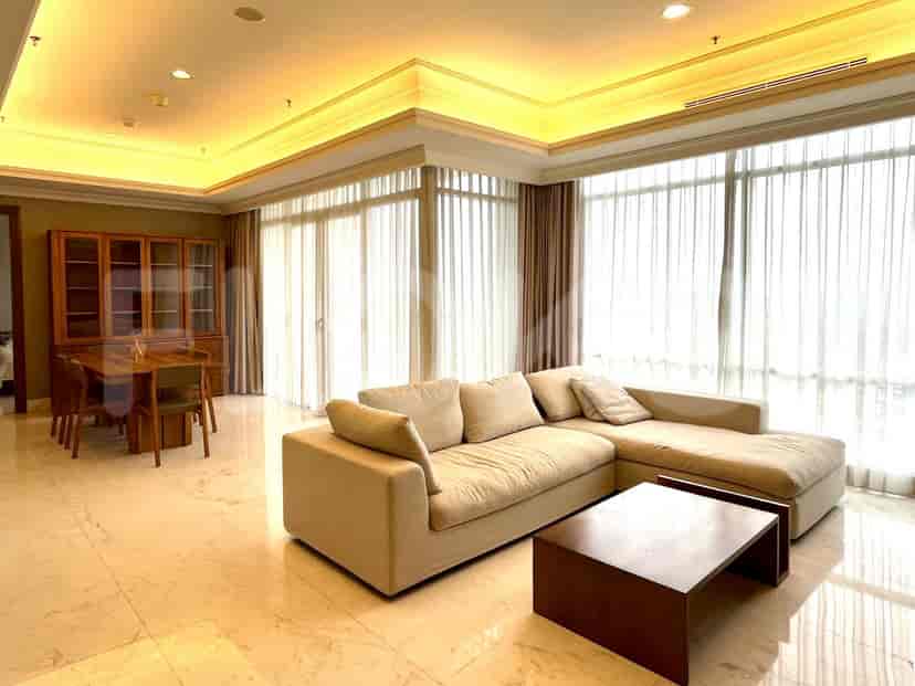 A modern living room with beige L-shaped sofa, coffee table, and large windows.