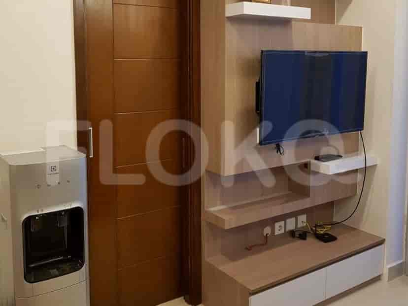 A media center with a wall-mounted TV, wooden shelving, and a water dispenser next to a door.