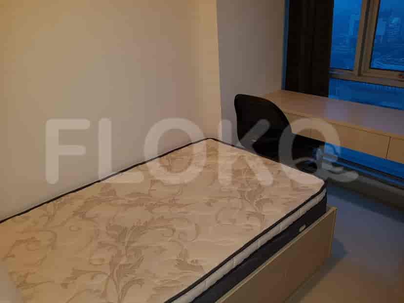 A bedroom with a single bed, a desk, and a window.