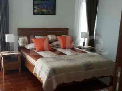 A bedroom with a bed, lamps, and paintings.
