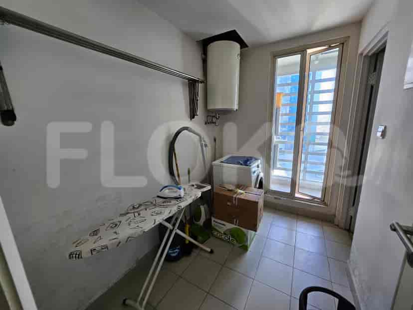 A small laundry area with a washing machine, ironing board, and drying rack.