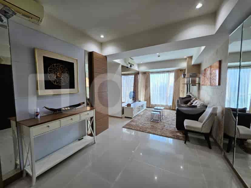 An expansive living room with mirrored walls, a console table, and access to the kitchen.