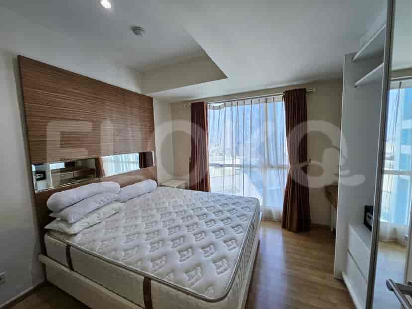 A master bedroom with a large bed, wooden headboard, and floor-to-ceiling windows.