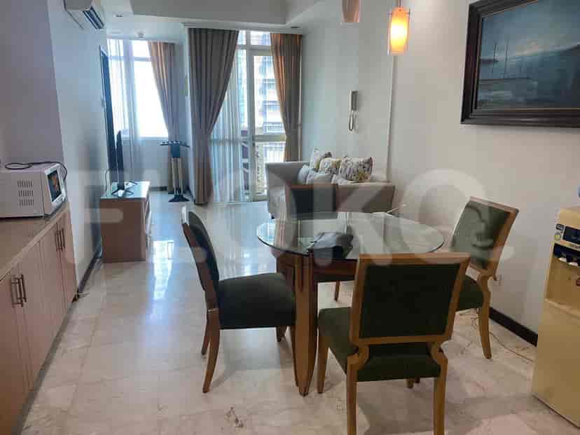 A living room with a glass dining table, sofa, and a window offering a city view.