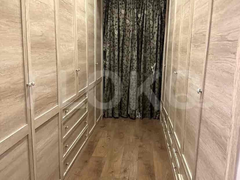 A walk-in closet with light wooden cabinetry and dark curtains.
