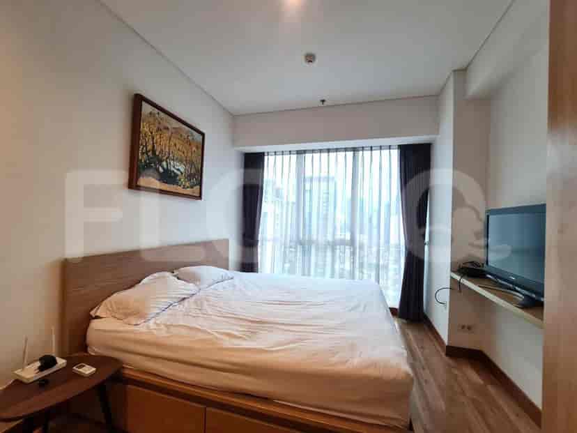 A bedroom with a large bed, wooden headboard, and a view of the city.