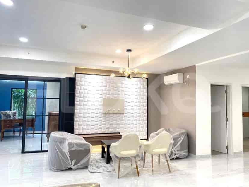 A modern living room with white panel wall, a black coffee table, and chairs covered in plastic.