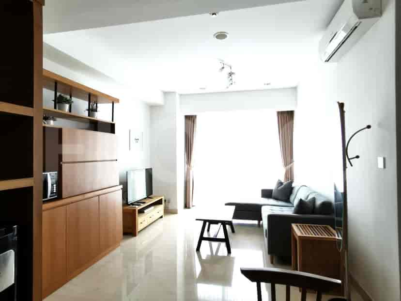 Bright living room with an L-shaped grey sofa, TV, and wooden storage.