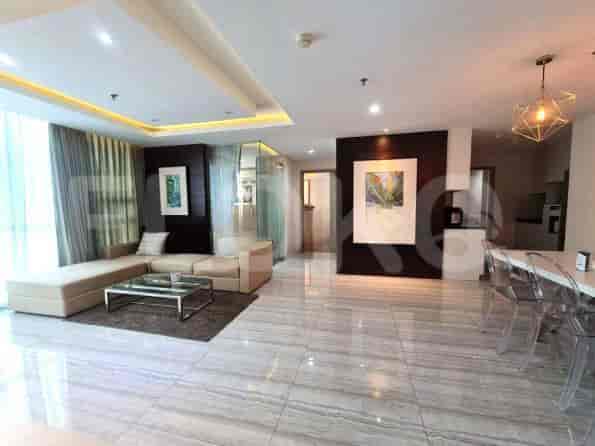 Spacious living room with a beige L-shaped sofa, glass coffee table, and art.
