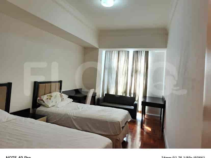 A bedroom with two beds and curtains.