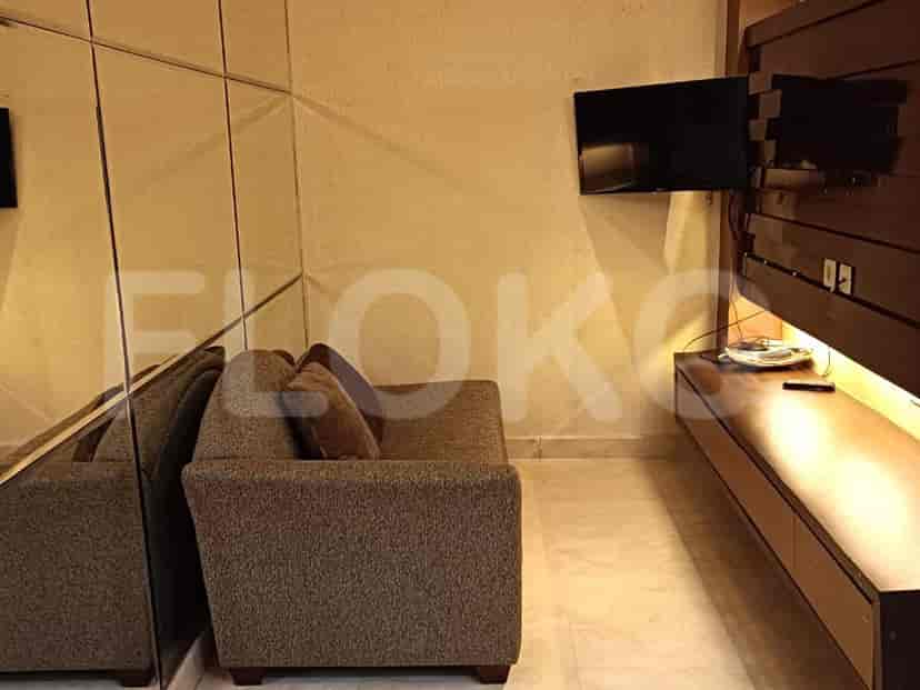 A cozy living area with a grey sofa, a wall-mounted TV, and a mirrored wall.