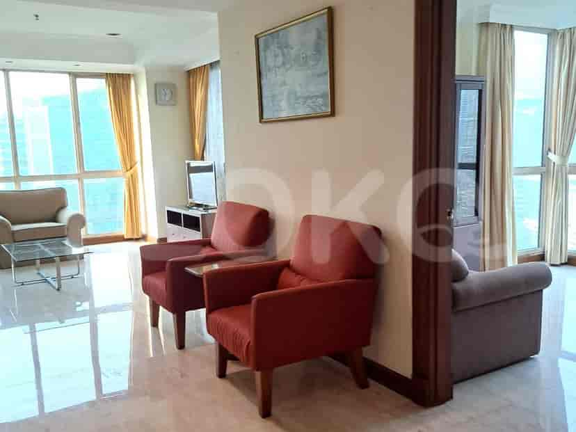 Living room with two red armchairs, a sofa, and large windows.