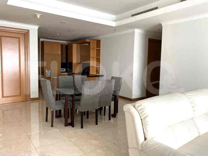 Area makan yang menampilkan meja kaca, kursi abu-abu, dan pemandangan ke arah dapur.
