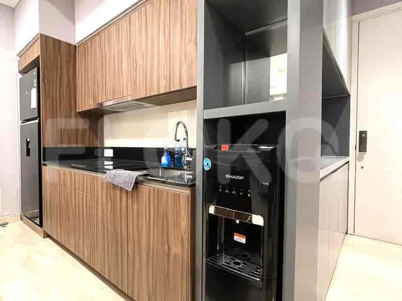 Dapur modern dengan lemari kayu, meja hitam, dan dispenser air.