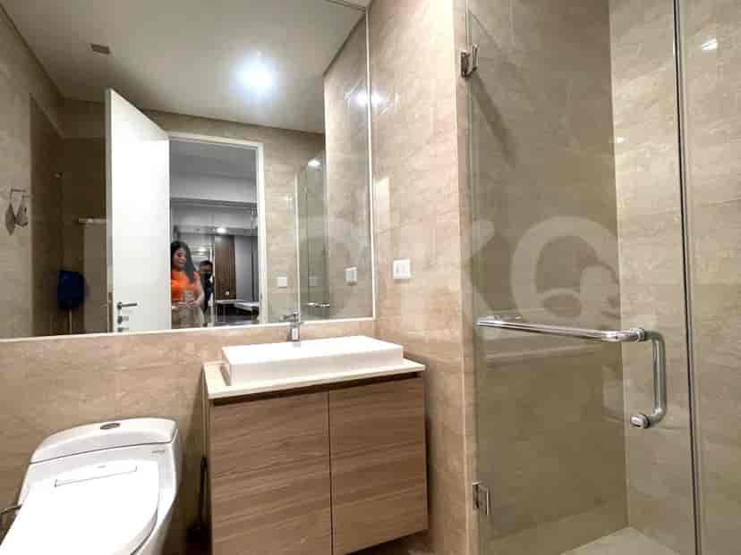 Kamar mandi dengan meja rias modern, cermin besar, dan kandang shower kaca.