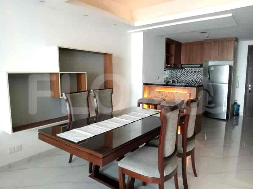 A dining room with a dark wooden dining table and chairs with a kitchenette in the background.