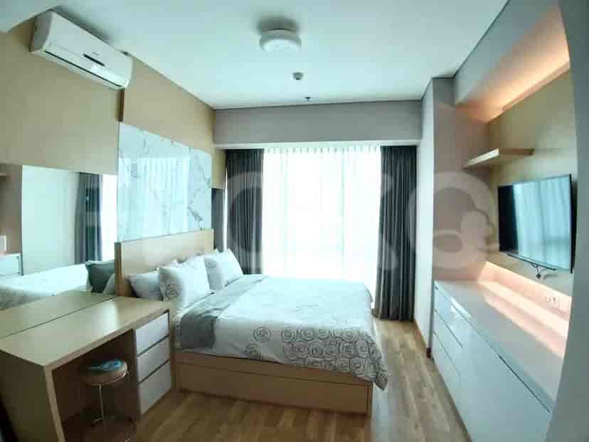 A bedroom with a bed, vanity, and large windows with curtains.