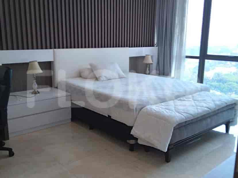 A well-lit bedroom featuring a bed with a large headboard and a seating bench.