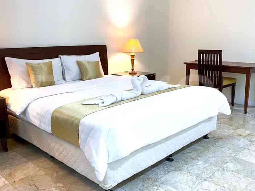 Kamar tidur dengan tempat tidur ukuran queen, meja kayu, dan meja samping tempat tidur.