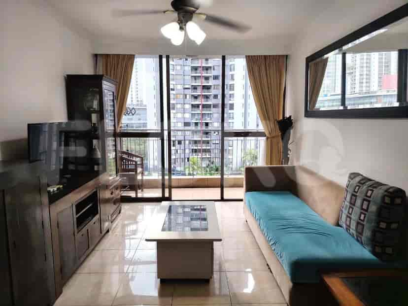 Living room with a balcony, featuring a sofa, entertainment unit, and a glass-top coffee table.