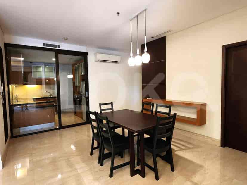 Area makan dengan meja, kursi, dan pemandangan ke dapur.