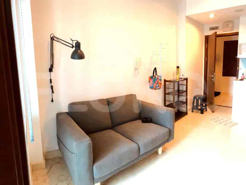 Ruang tamu dengan sofa abu-abu, lampu dinding, dan elemen dekoratif.