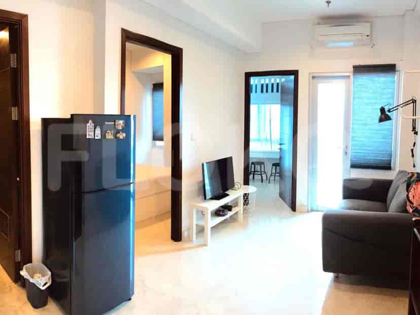 Ruang tamu dengan sofa, TV, dan akses ke dapur.