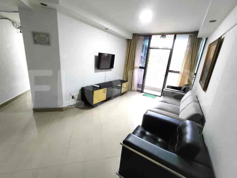 A spacious living room featuring a TV mounted on the wall, a sofa, and a black chair.