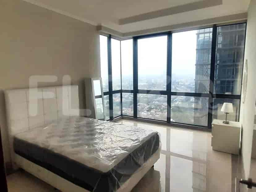 A bedroom with a large window, bed and a mirror.