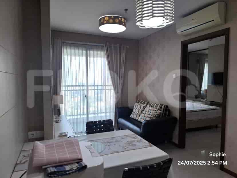 A dining table set and a black sofa near a large window with sheer curtains.