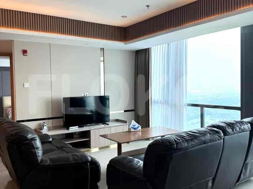 A modern living room with black leather sofas, a large TV, and a view.